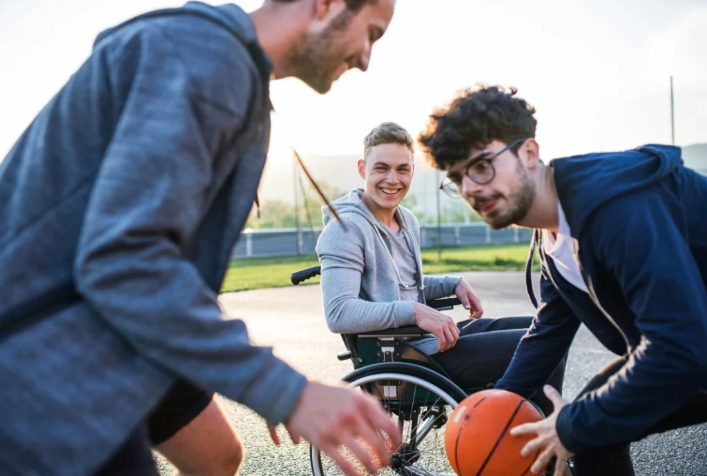 Three friends, one disabled in wheelchair, playing basketball outside