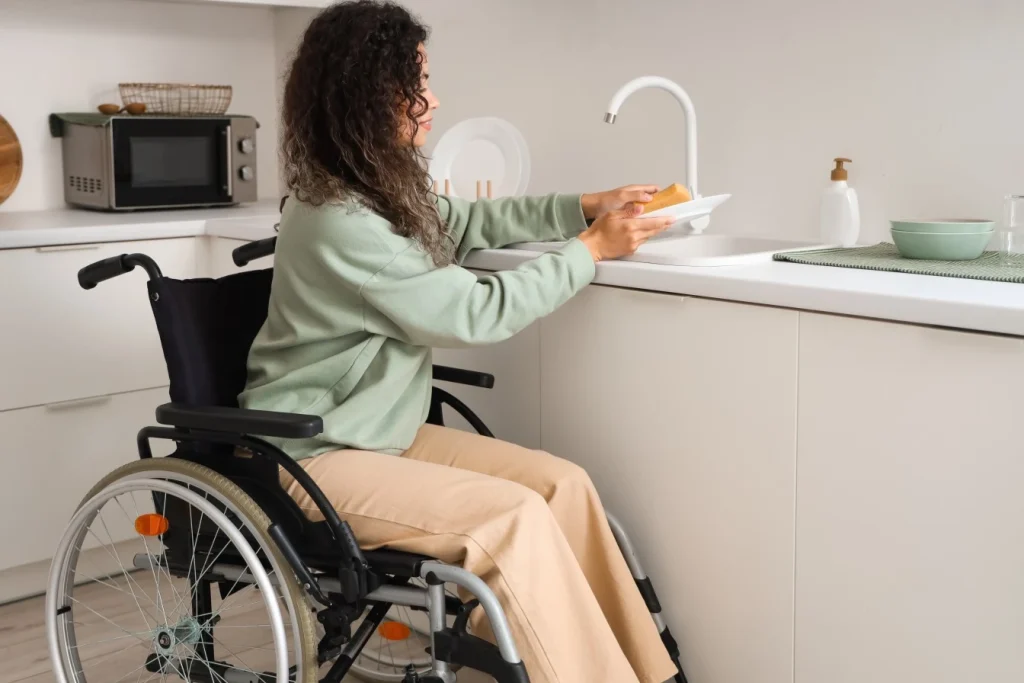 Disabled woman in wheelchair doing the dishes at home